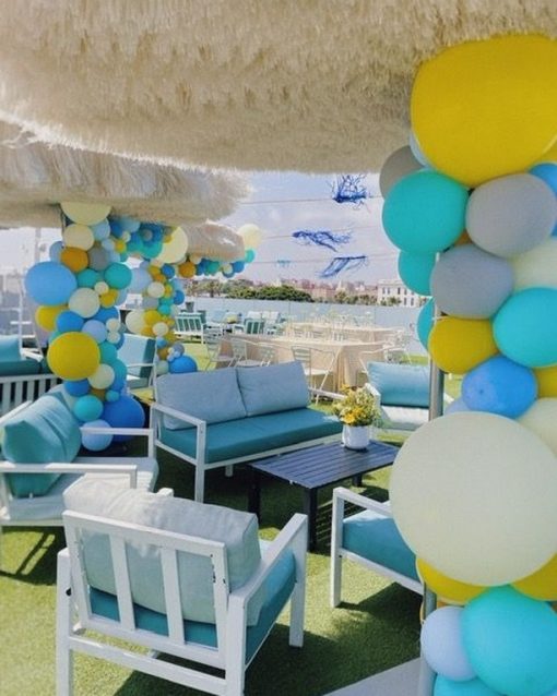 Guirnaldas de globos azules, turquesa, amarillos y blancos en la terraza de un bautizo en El Camarote & The Roof