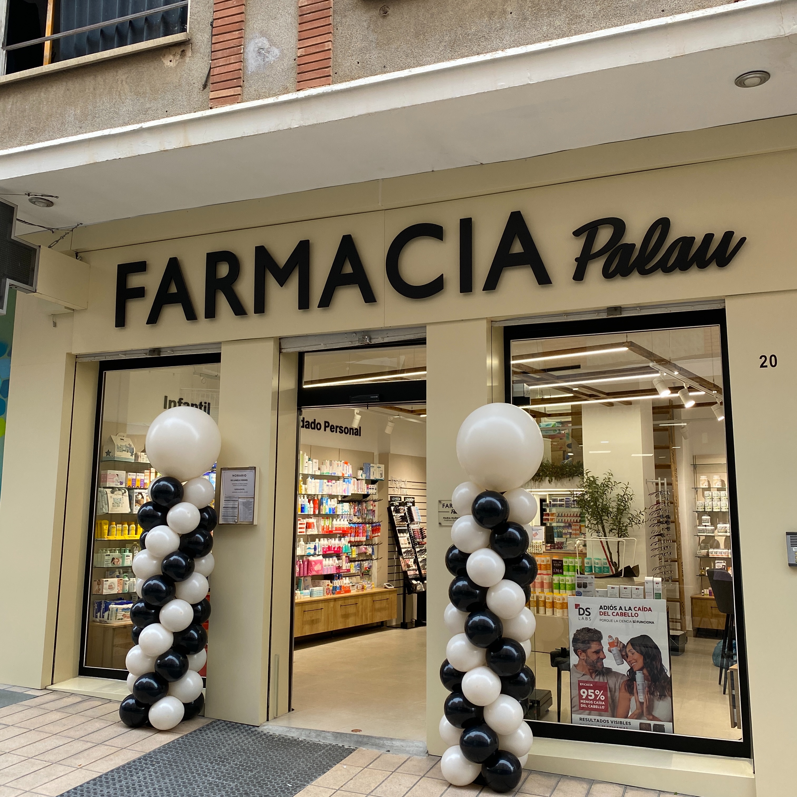 Columnas de globos blancos y negros junto a la entrada de Farmacia Palau en Benaguasil