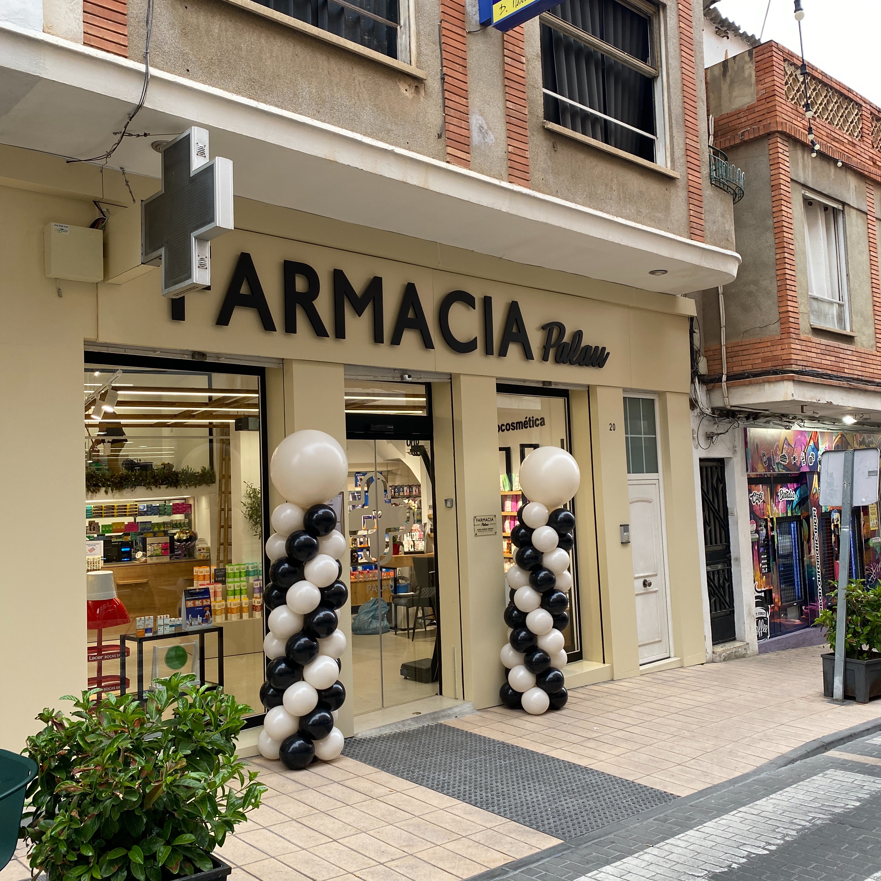 Decoración exterior con globos para comercio en la fachada de Farmacia Palau en Benaguasil