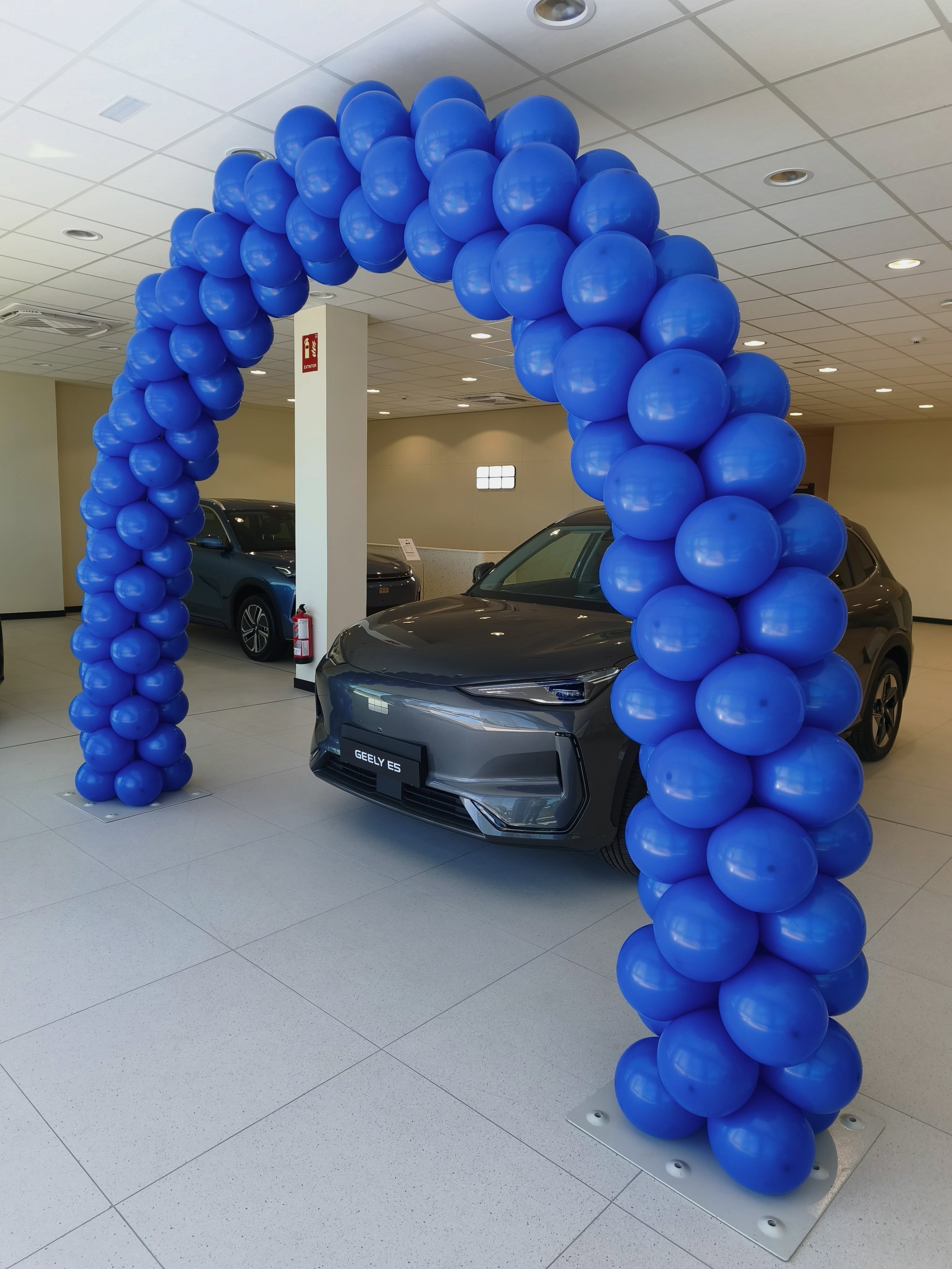 Vista lateral de arco de globos azul junto a coche Geely