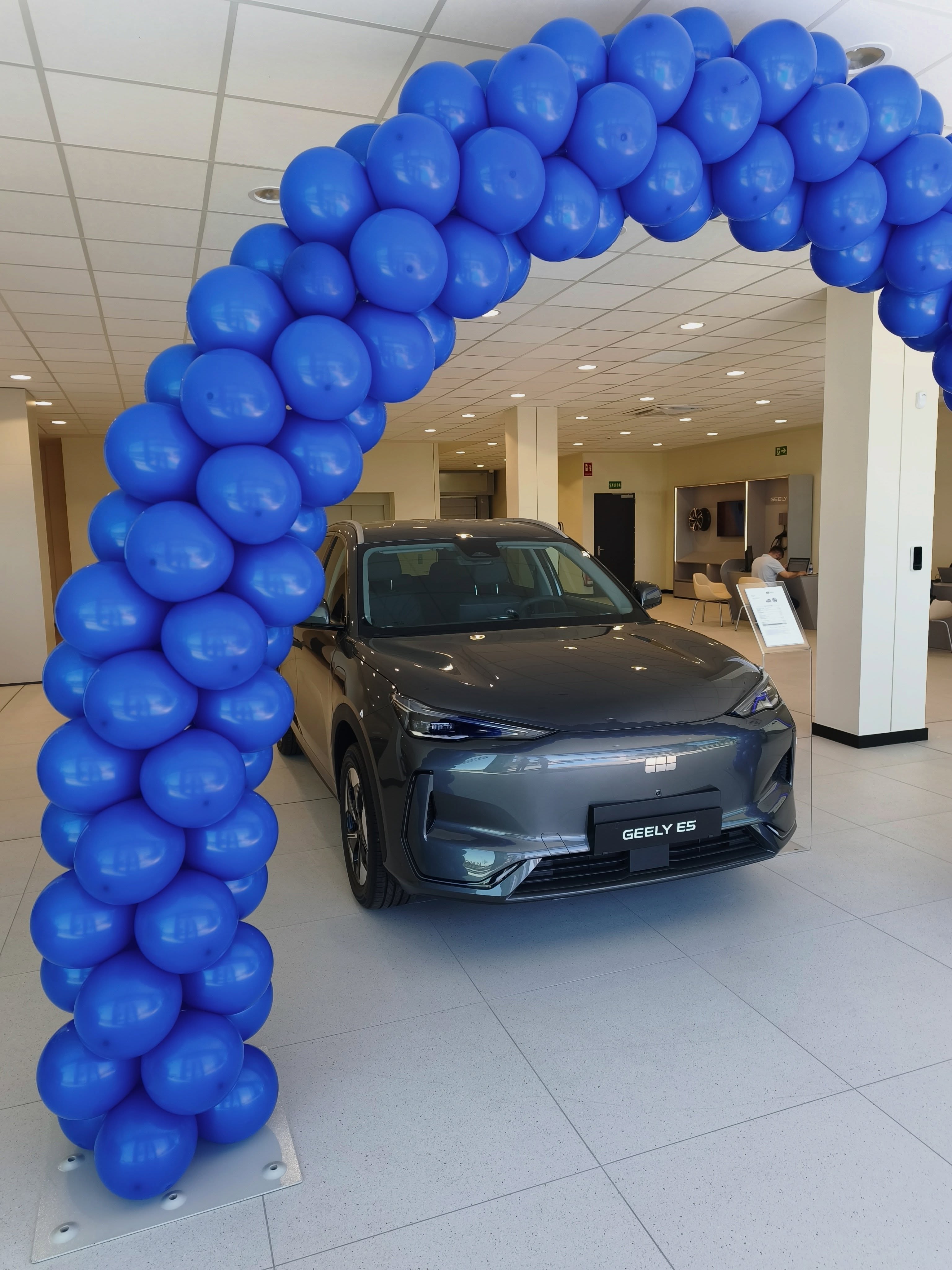 Arco de globos azul para entrega de coche Geely en concesionario