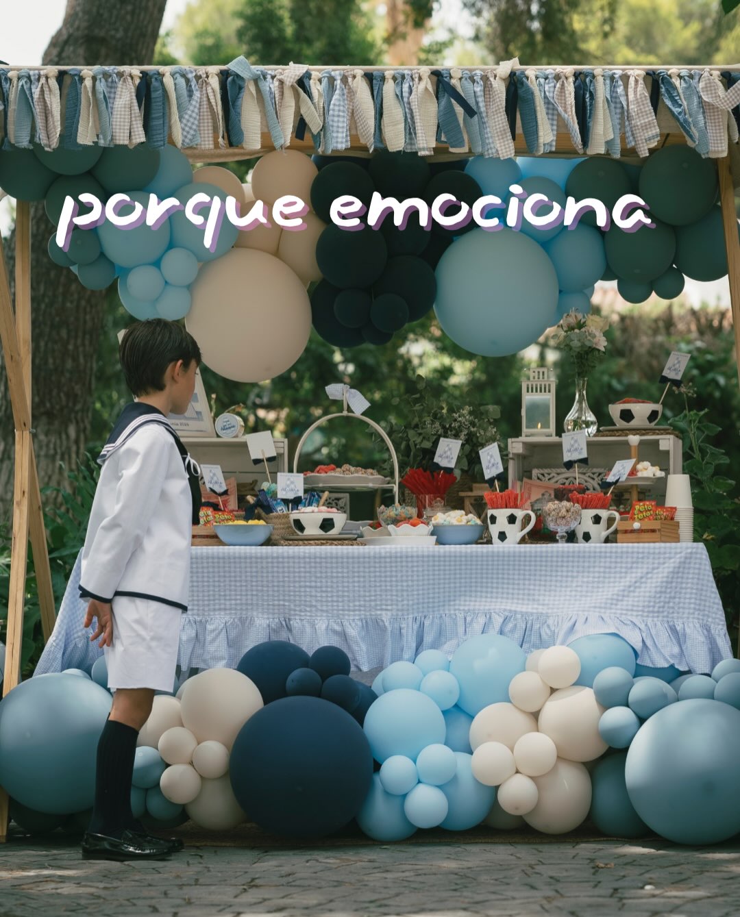 Mesa dulce exterior de comunión con base de globos azules, blancos y crema