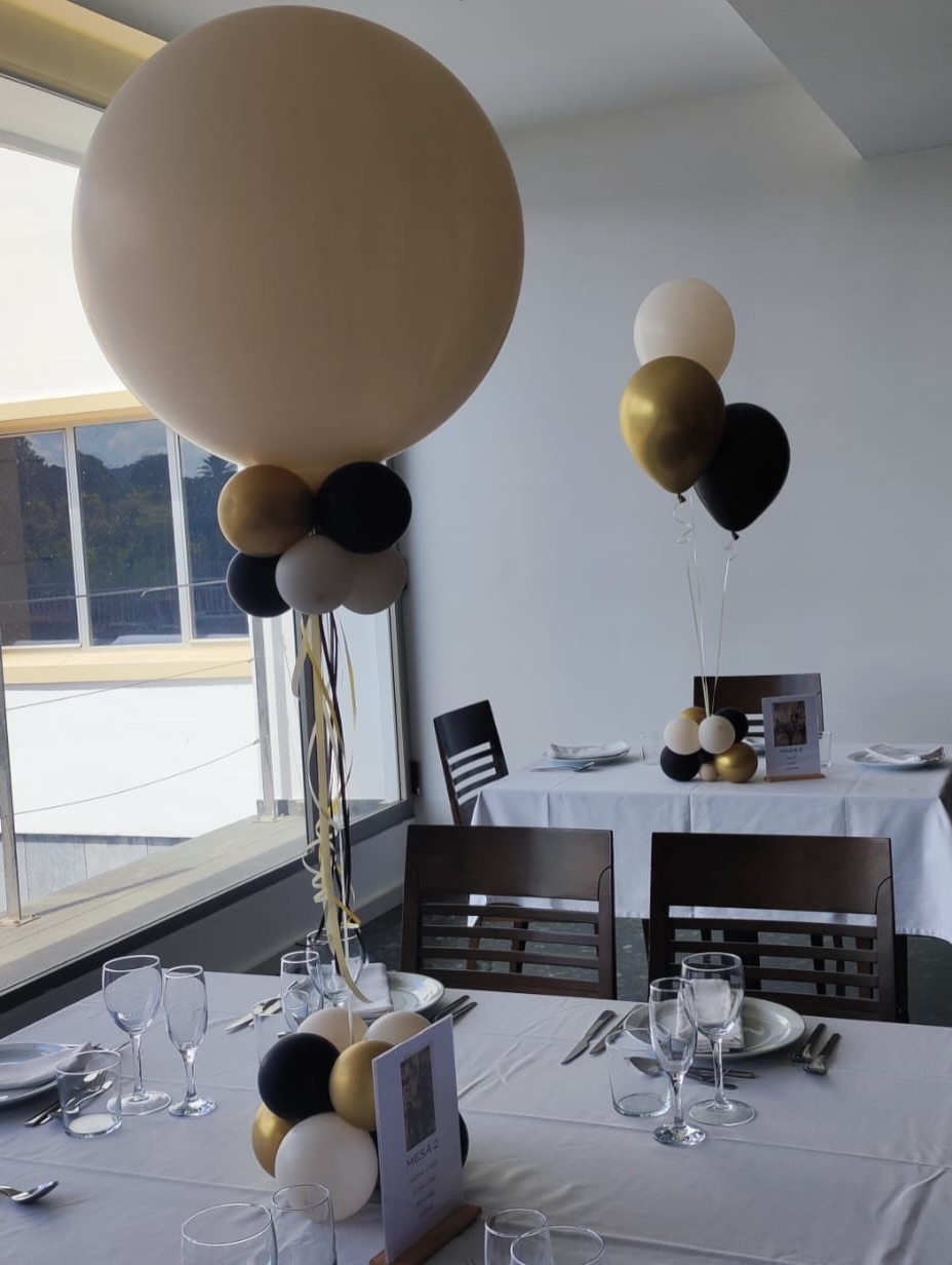 Centro de mesa con globo crema grande y base de globos negros, dorados y marfil