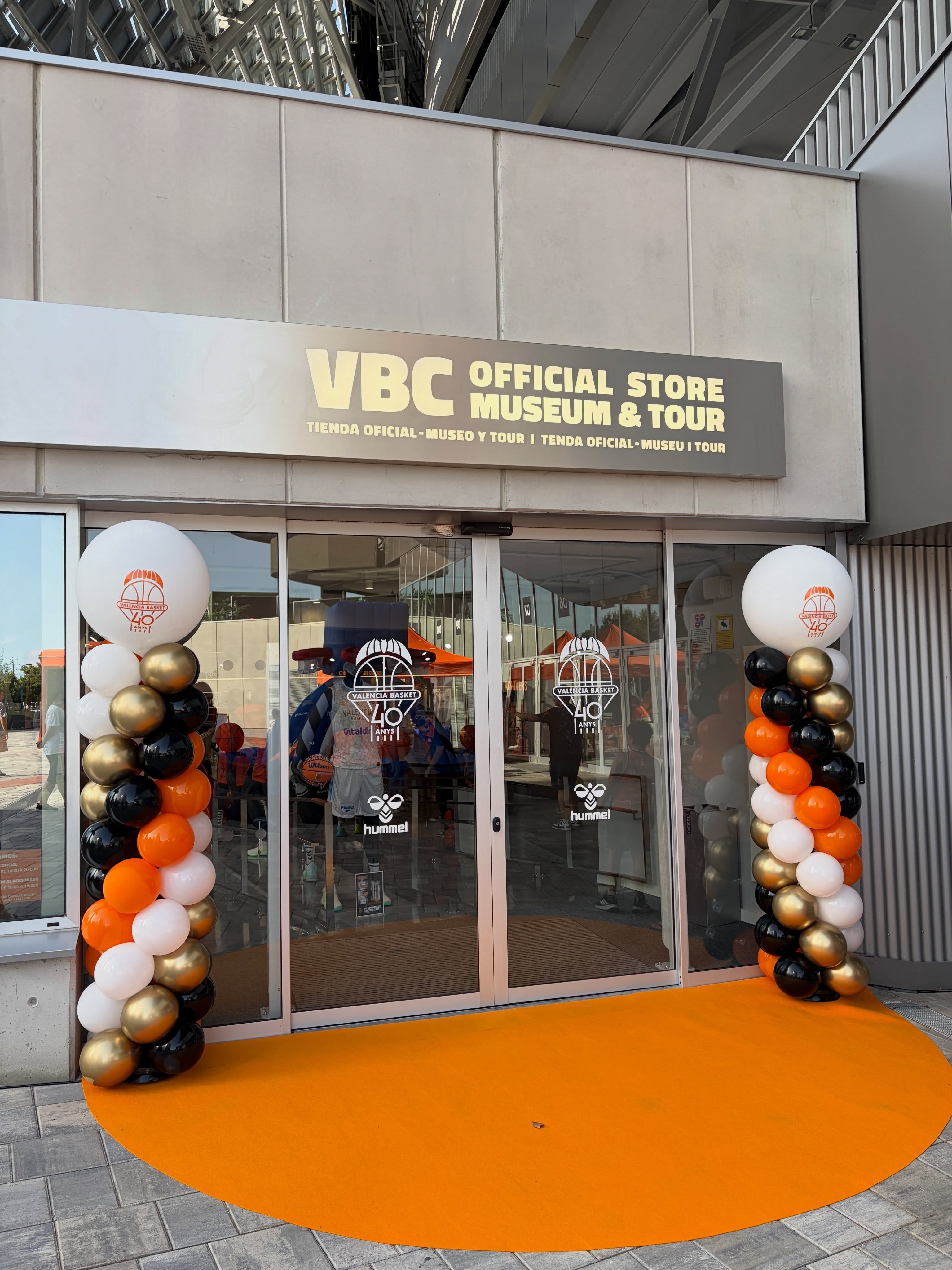 Entrada de la tienda de Valencia Basket con dos columnas de globos naranjas, negros, blancos y dorados